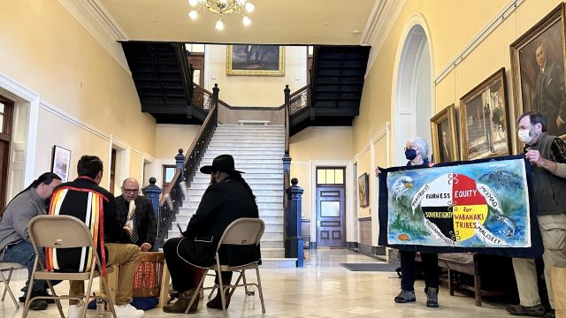 Passamaquoddy Tribal
Representative Aaron Dana (facing viewer), then clockwise Wambli
Martinez, Amuwes Dana and Nicholas Paul drum in the Hall of Flags
for the 2023 Wabanaki Alliance Lobby Day. Barbara and Terry Baker
hold the banner.