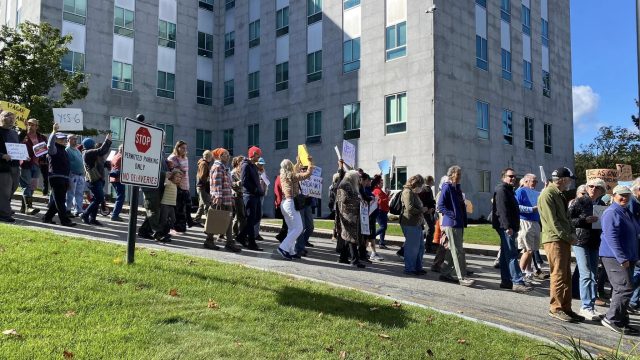 After the rally, participants took part in a march around the State House. Photo: First Congregational Church UCC, South Portland, ME Group of people marching for Wabanaki sovereignty in front of gray building