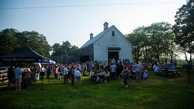 More than 200 people attended Nihkaniyane: Let’s Go Forward Together at Mallet Barn, Wolfe’s Neck Center, in Freeport. Large crowd gathers for an event outside at sunset in front of a large white barn.
